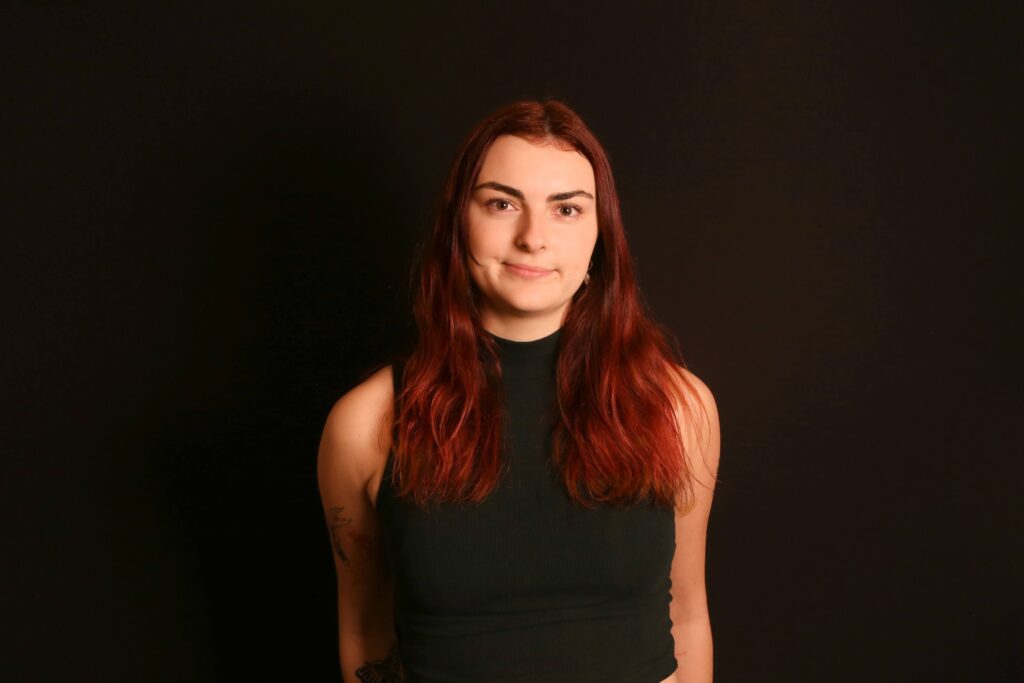 Image of Lucy Palmer wearing a black sleeveless top on a black background