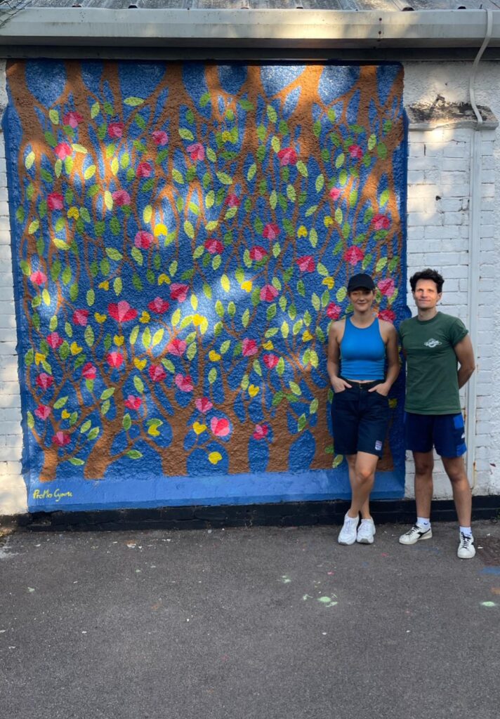 Augustė and Daniele from ProMo stood next to the mural at North Ely Youth Club